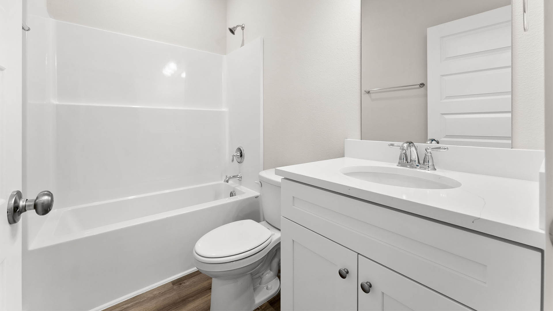 Bathroom with quartz countertops and single vanity and white cabinets and EVP flooring and toilet and shower.