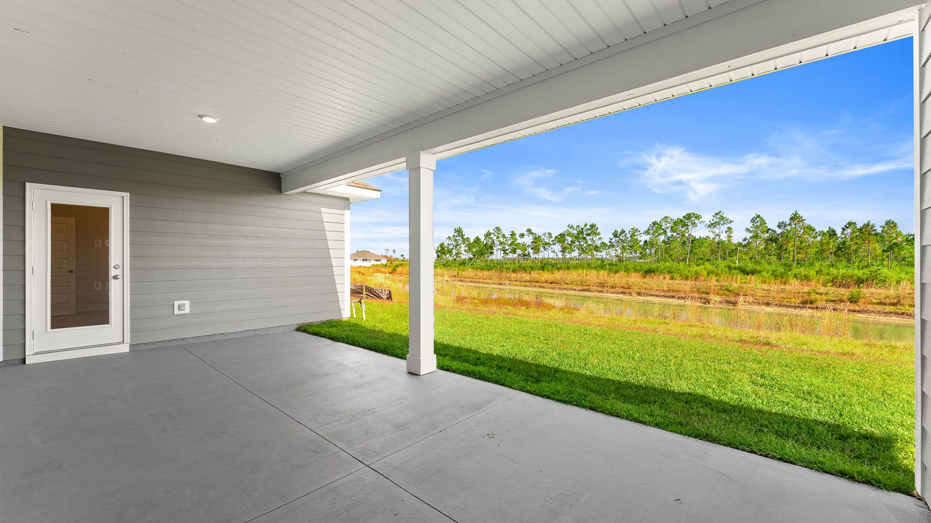Covered back patio and backyard view and primary bedroom door entrance.