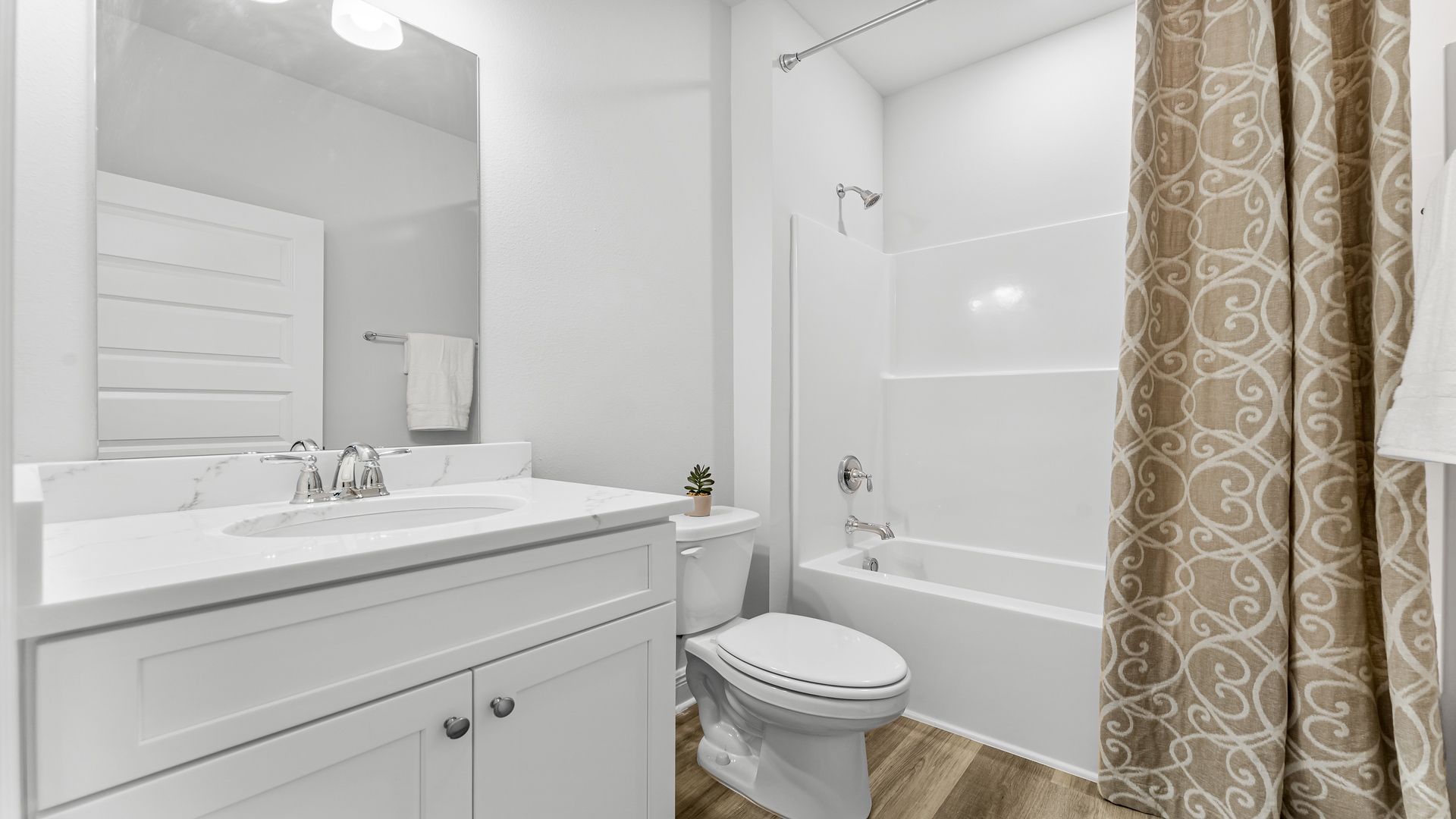Bathroom with EVP flooring and white cabinets with quarts countertop and single vanity and shower and toilet.