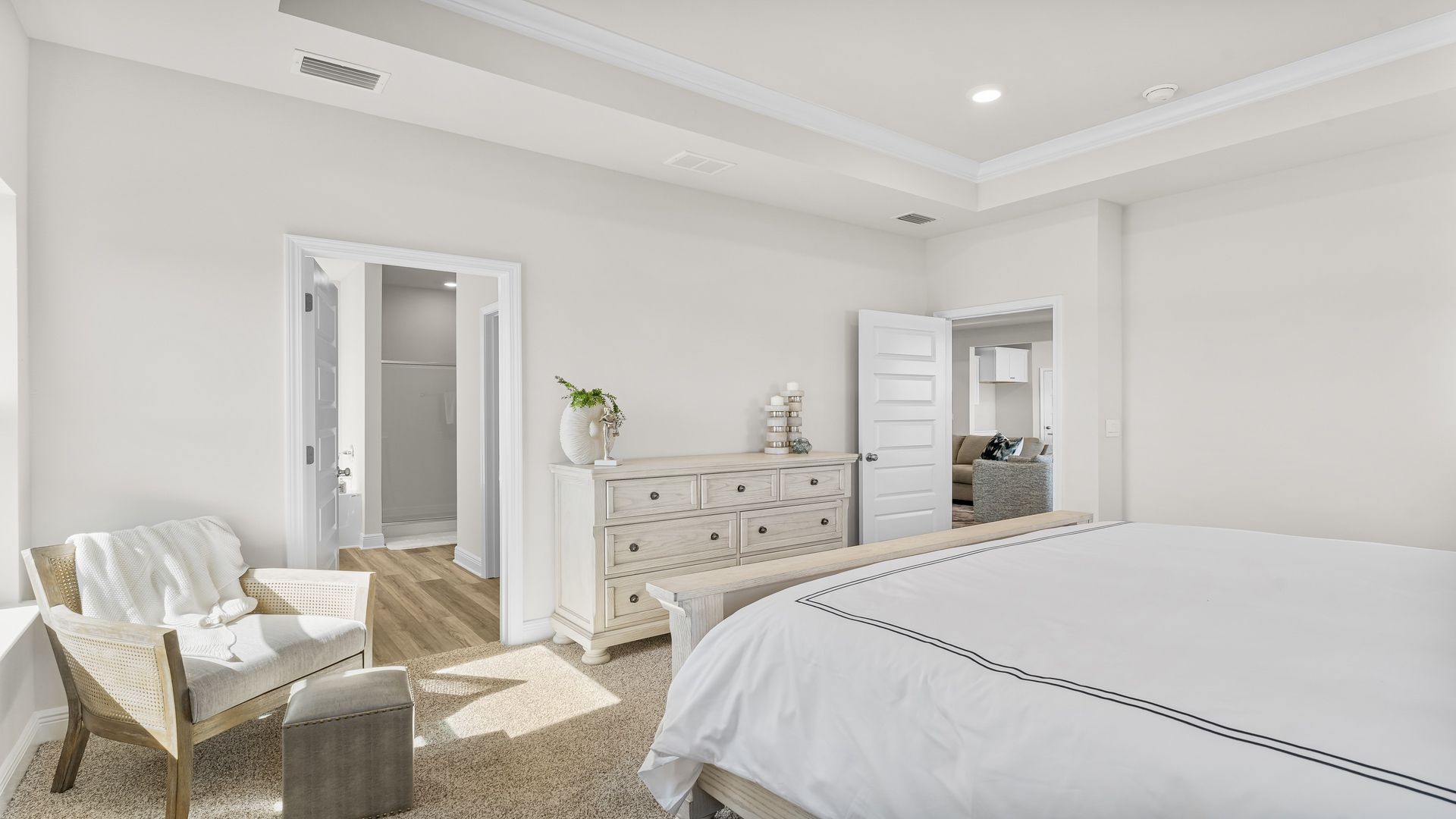 Primary bedroom with carpet floors and tray ceilings with bathroom entrance.
