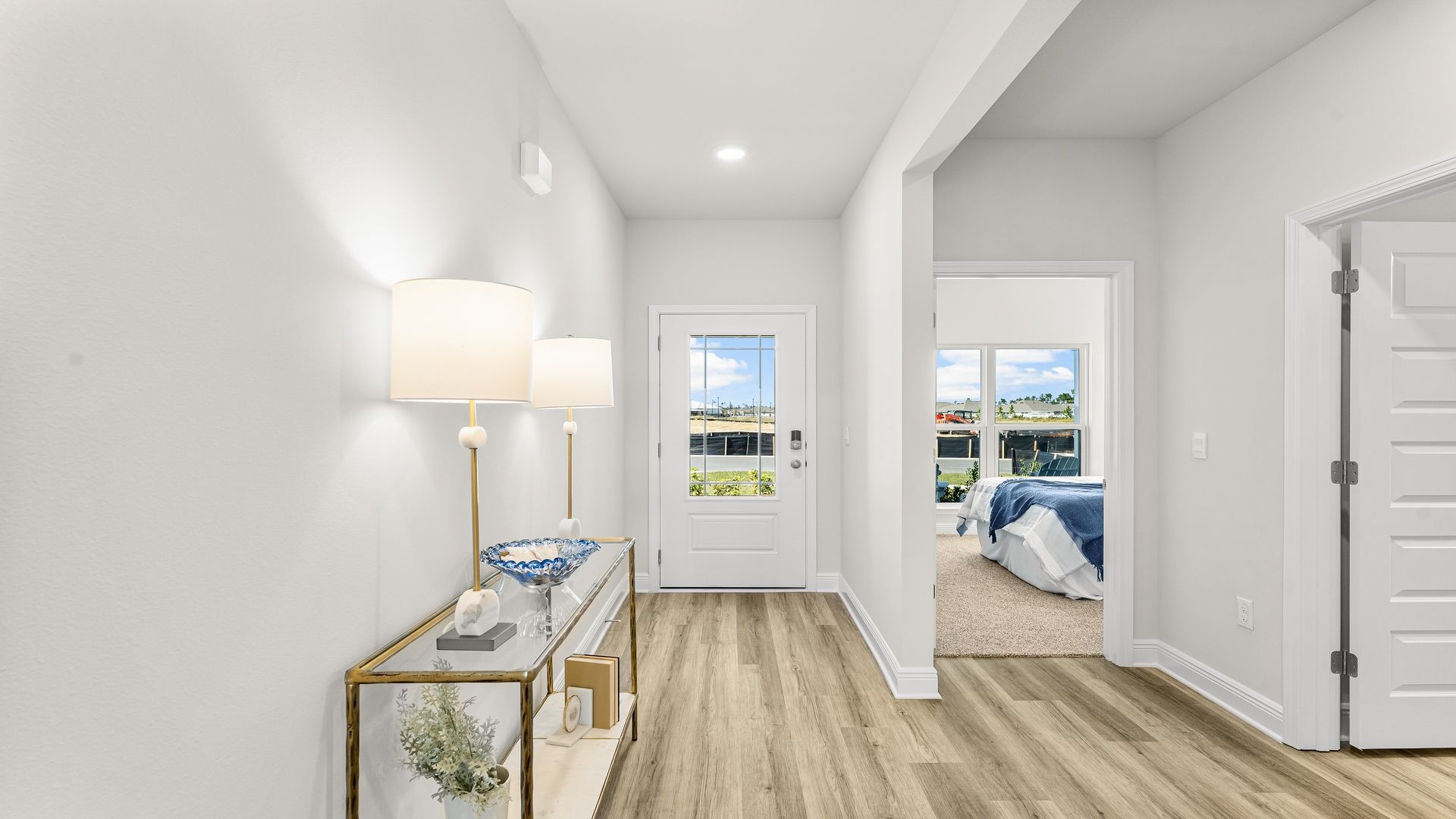 Front foyer with EVP flooring and prairie-style front door next to bedroom and bathroom.
