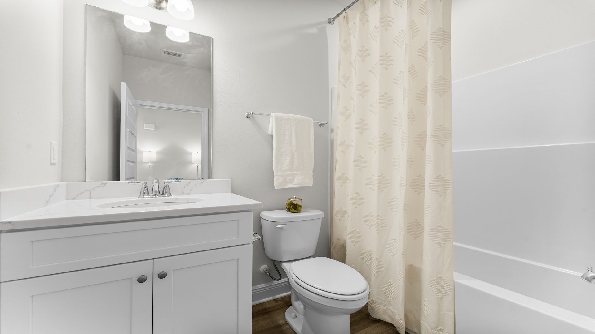 Bathroom with EVP flooring and white cabinets with quarts countertop and single vanity and shower and toilet.