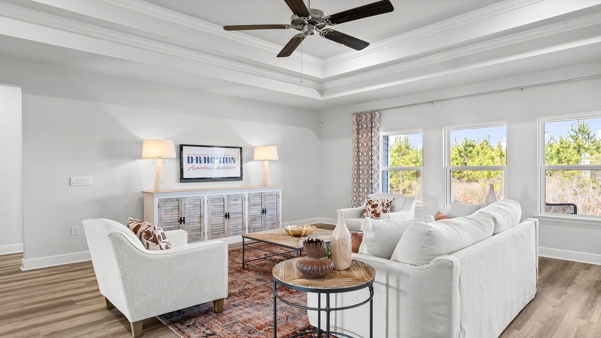 Open living room with EVP flooring and tray ceilings and ceiling fan and 3 windows.