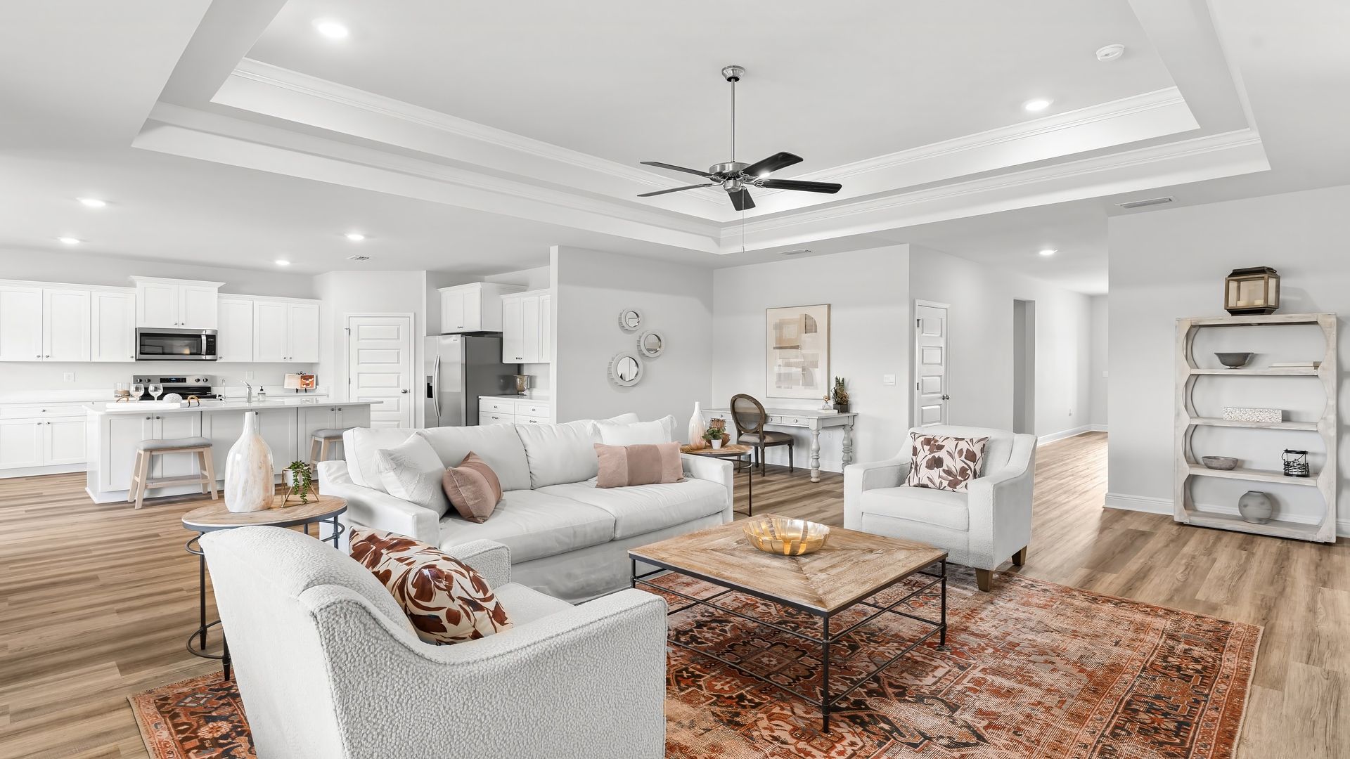 Open living room with EVP flooring and tray ceilings and ceiling fan.