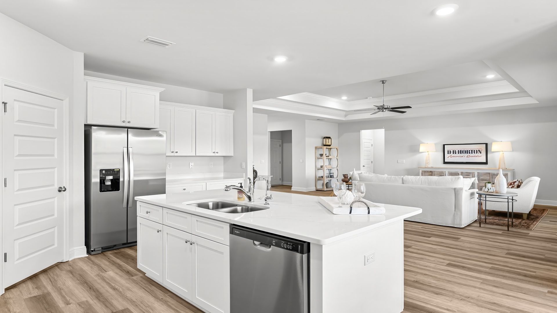 Kitchen with island with white cabinets and quartz countertops and pantry and stainless-steel appliances.