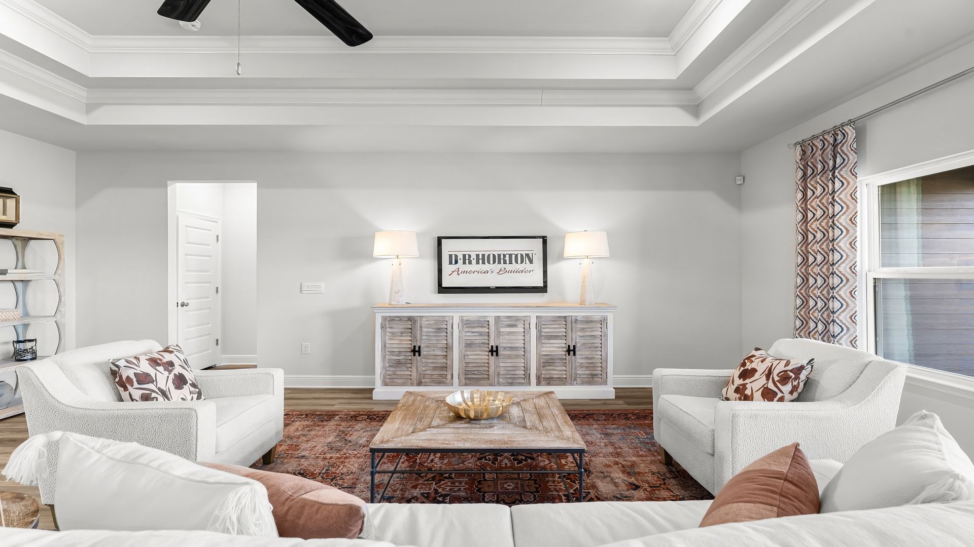 Open living room with EVP flooring and tray ceilings and ceiling fan and 3 windows.