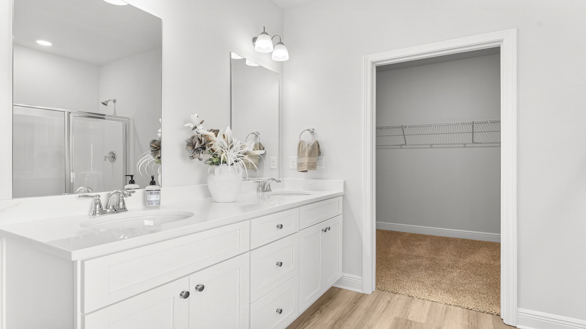 Primary bathroom white cabinets and double vanity with quartz countertops.