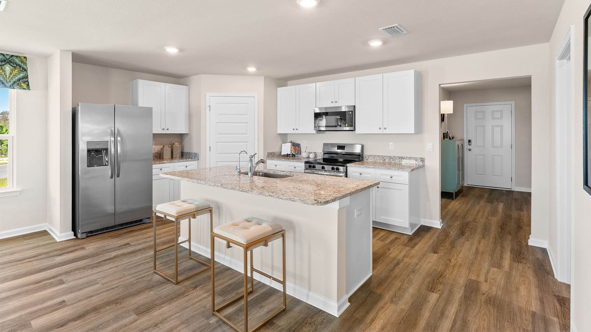 Kitchen with island and white cabinets and stainless-steel appliances and granite countertops.