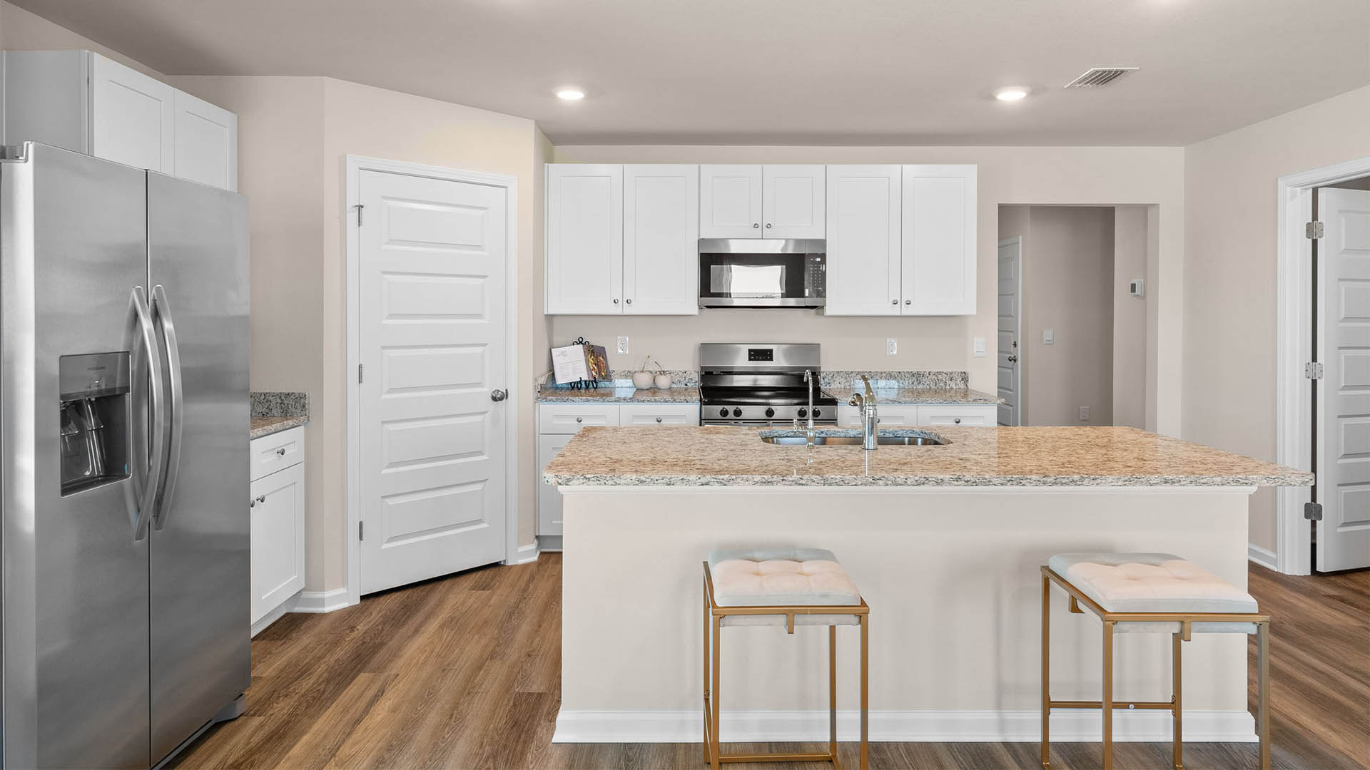 Kitchen with island and white cabinets and stainless-steel appliances and granite countertops.