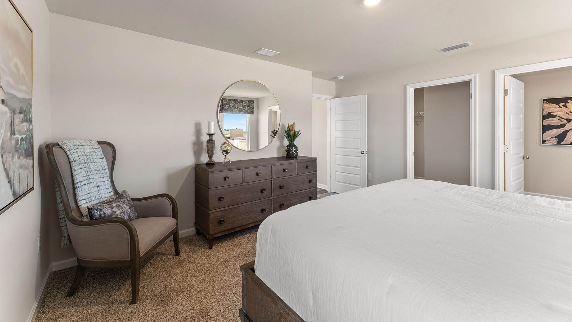 Primary bedroom with carpet floor and two windows and bathroom and closet entrance.
