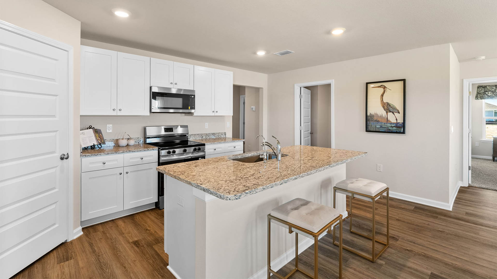 Kitchen with island and white cabinets and stainless-steel appliances and granite countertops.
