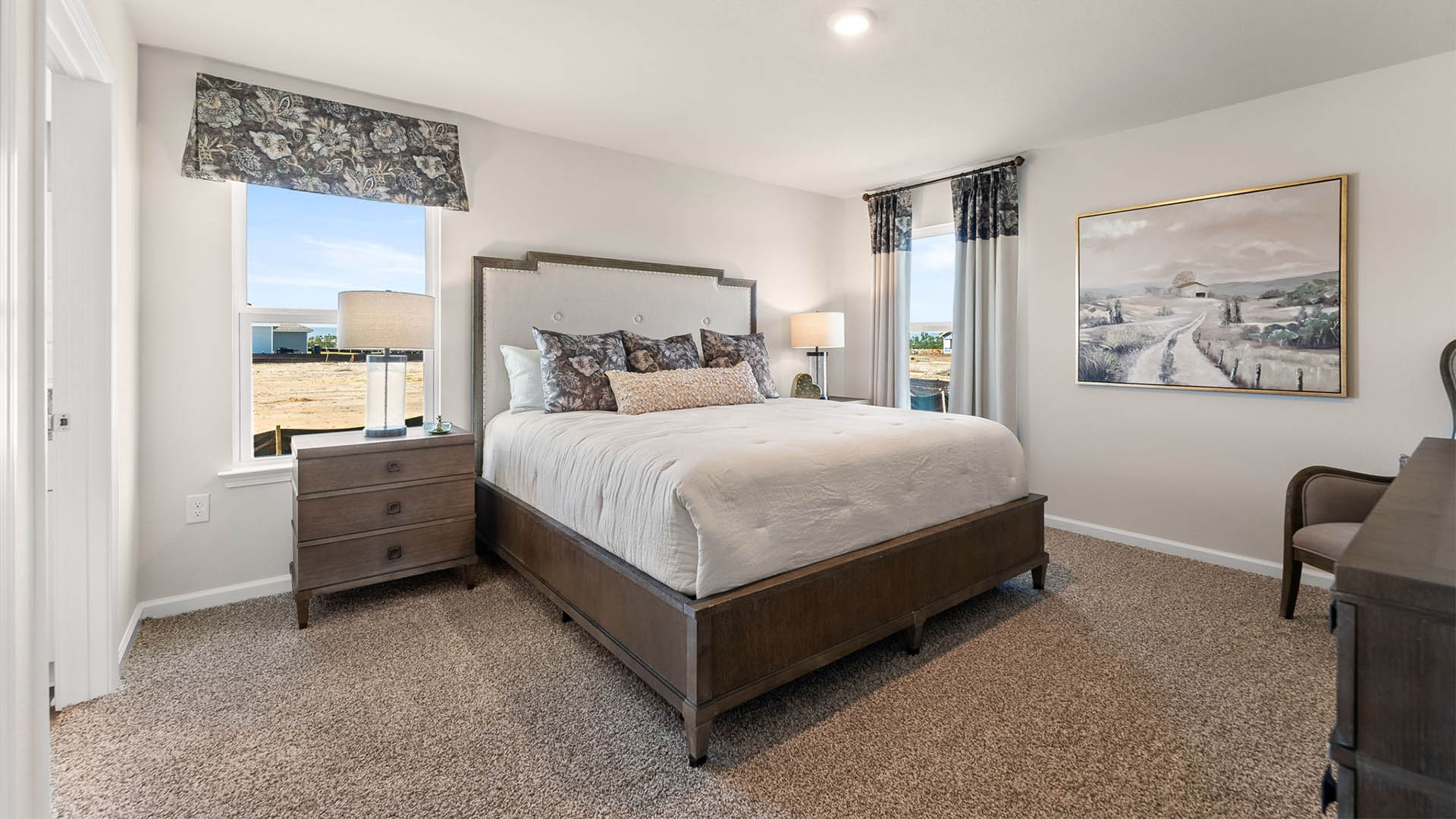 Primary bedroom with carpet floor and two windows and bathroom and closet entrance.