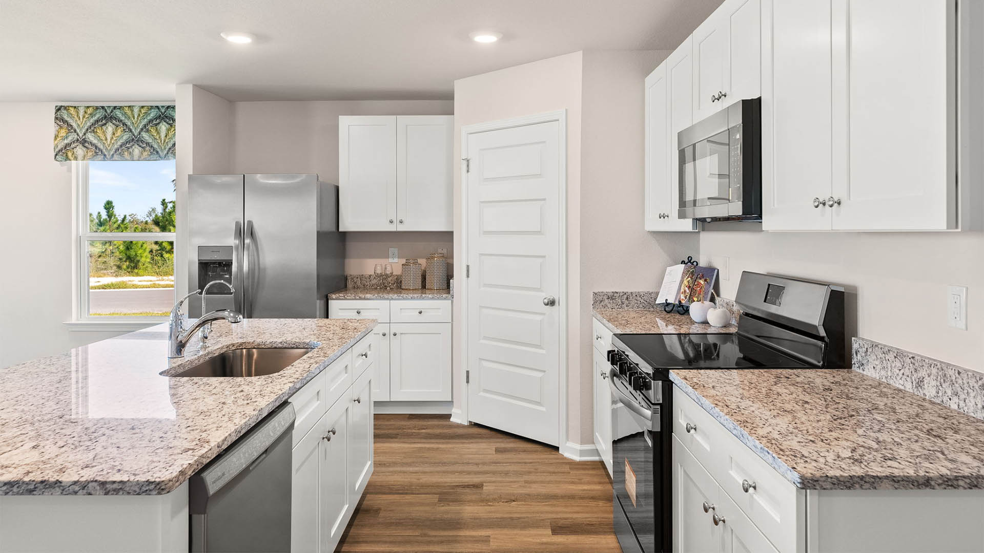 Kitchen with island and white cabinets and stainless-steel appliances and granite countertops.