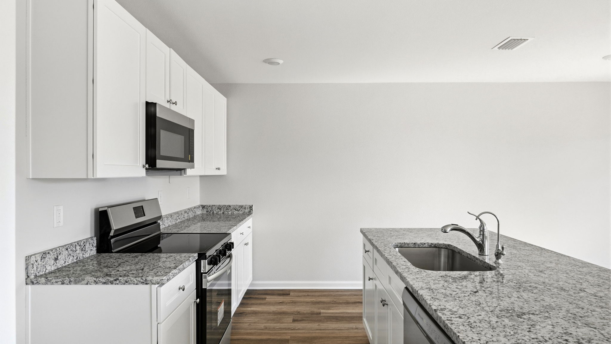Kitchen and with island and granite countertops and stainless-steel appliances.