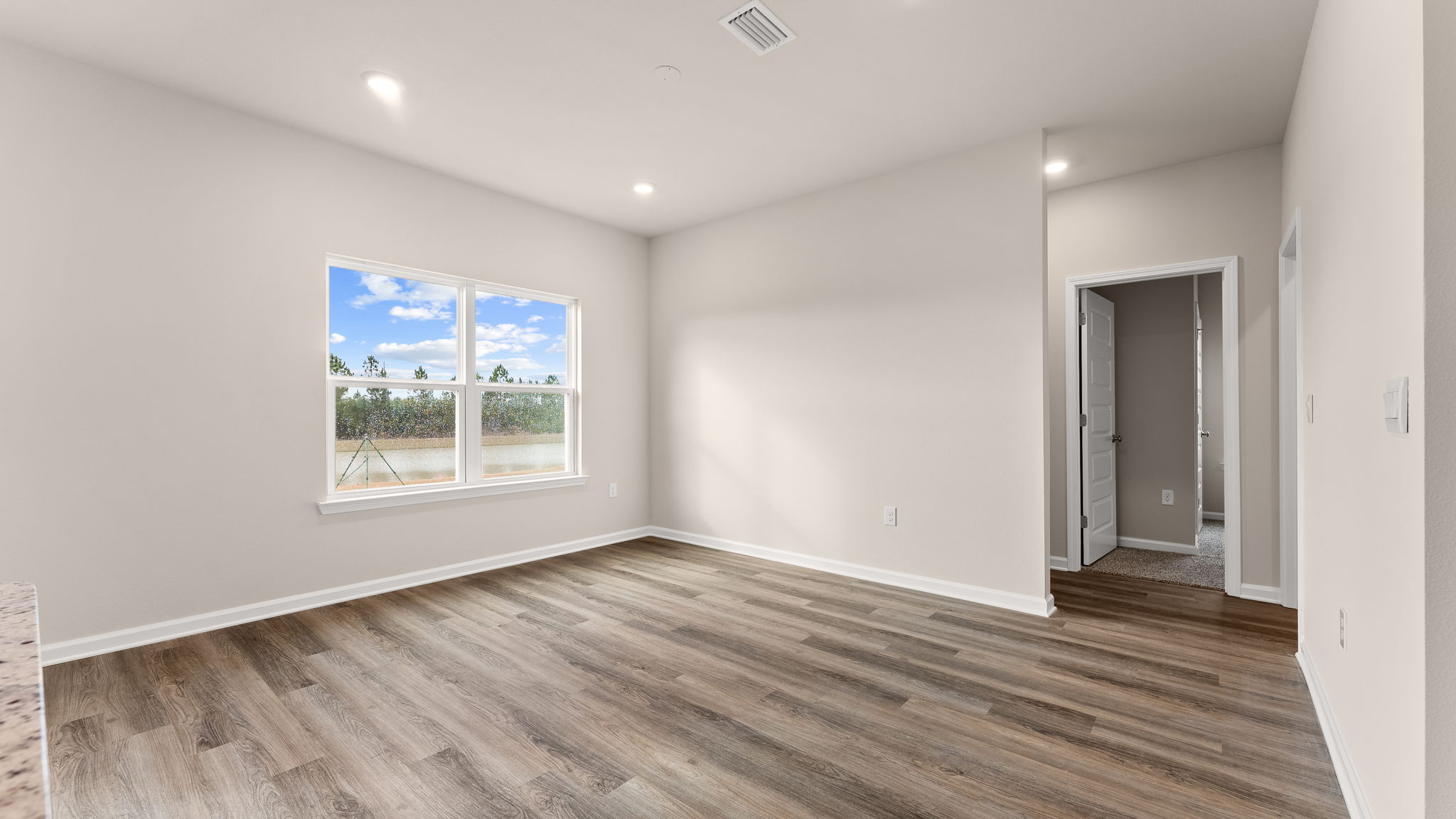 Living room with EVP flooring and windows next to bedrooms.