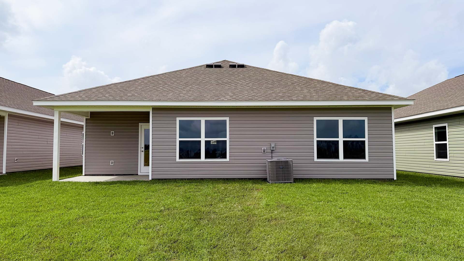 Beau plan rear of home with concrete pad and back yard.