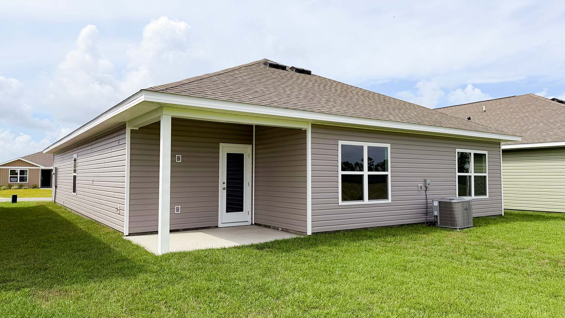 Beau plan rear of home with concrete pad and back yard.