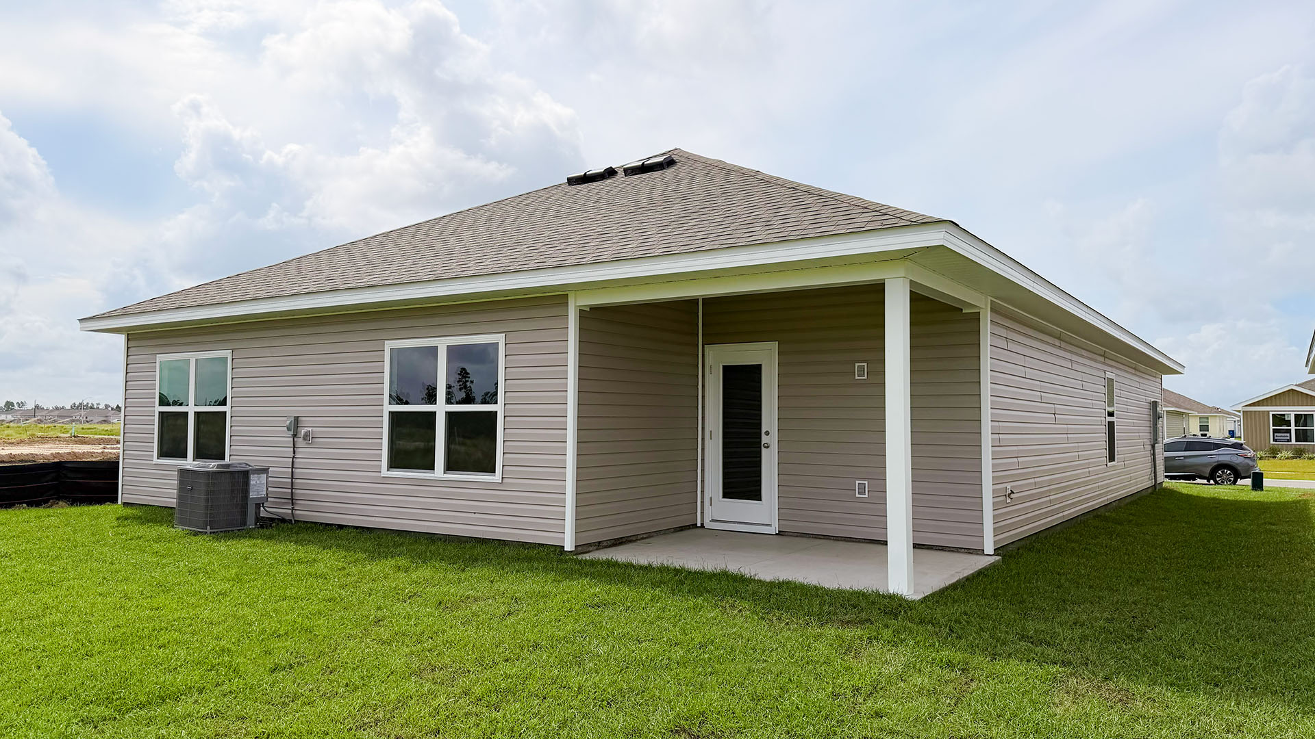 Beau plan rear of home with concrete pad and back yard.