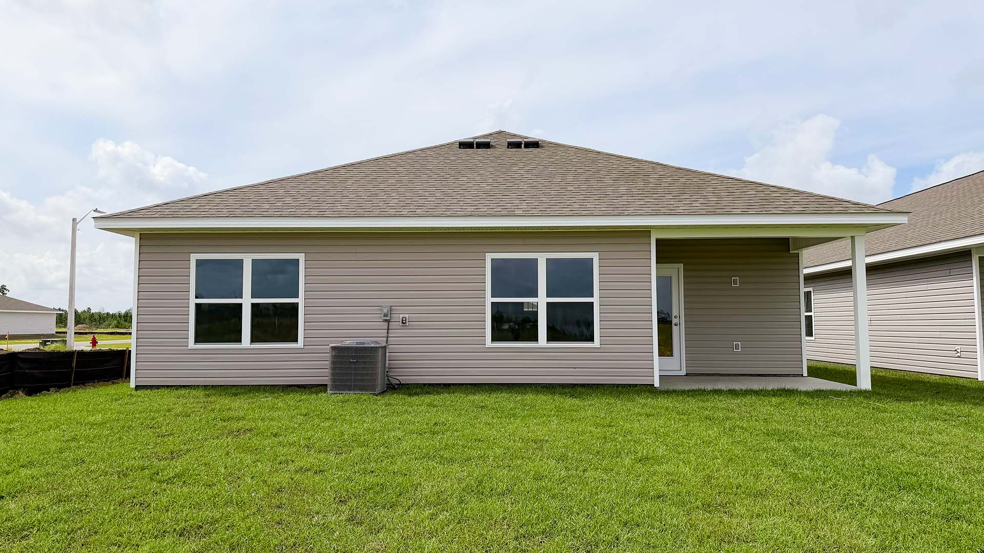 Beau plan rear of home with concrete pad and back yard.