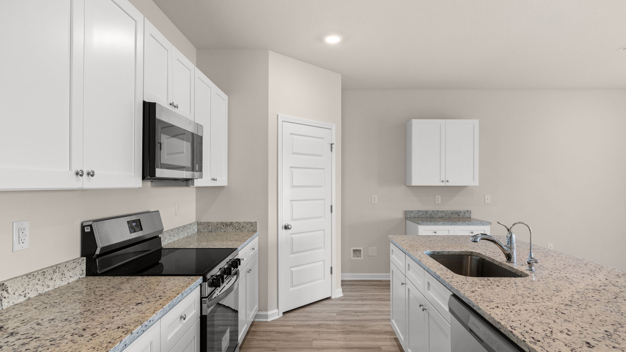 Kitchen with island and granite countertops with white cabinets and stainless-steel appliances.