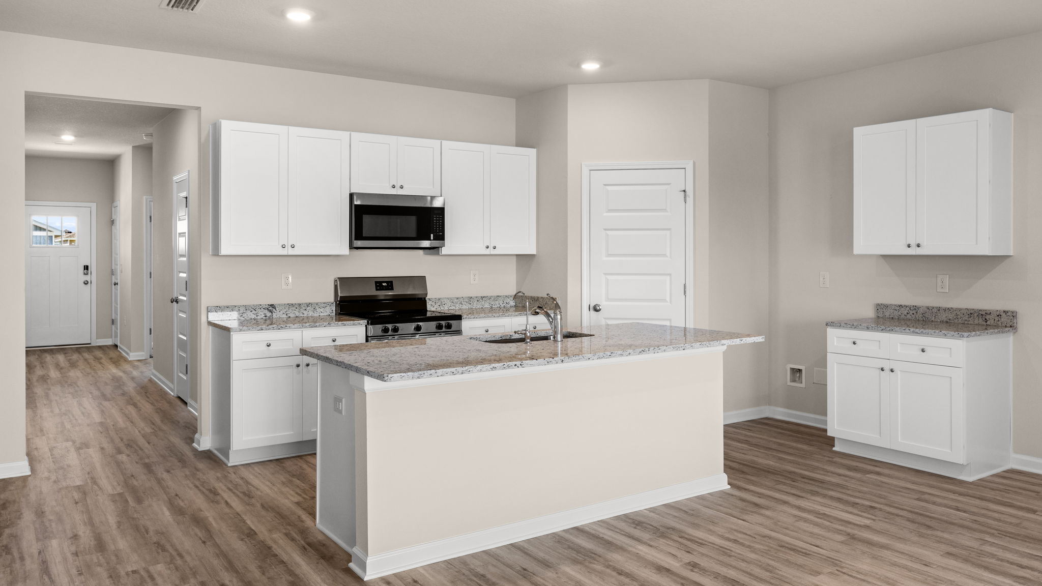 Kitchen with island and granite countertops with white cabinets and stainless-steel appliances.