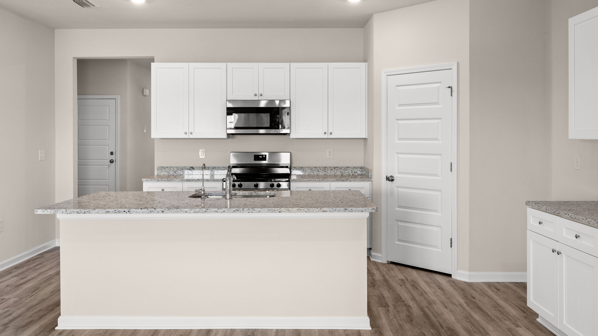 Kitchen with island and granite countertops with white cabinets and stainless-steel appliances.