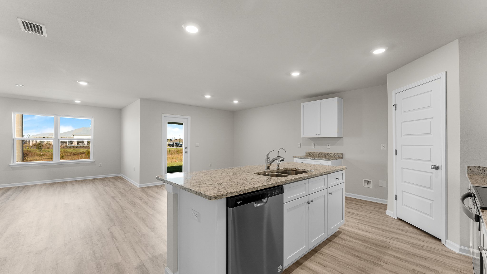 Kitchen island with white cabinets and stainless-steel appliances and granite countertops.