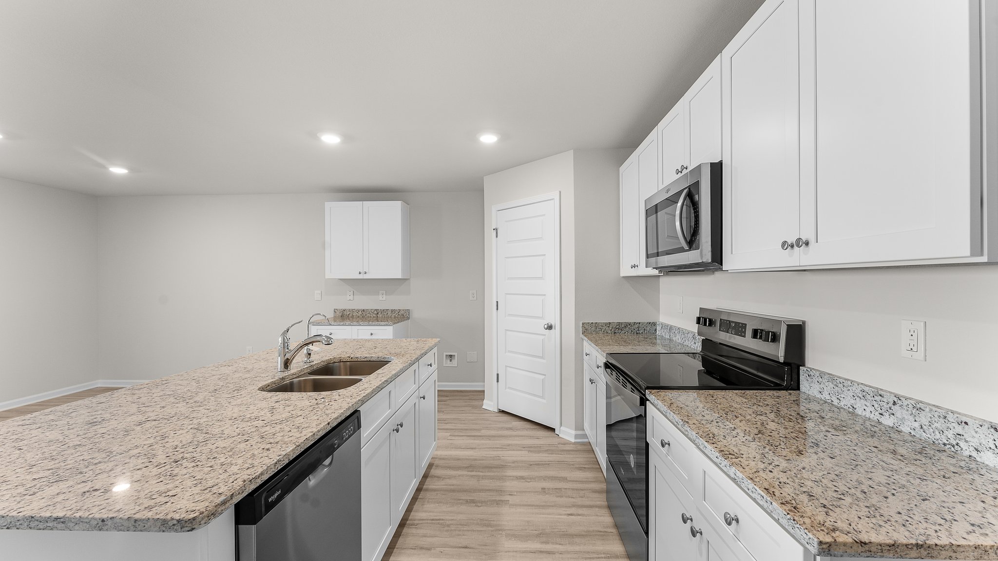 Kitchen island with white cabinets and stainless-steel appliances and granite countertops and pantry.