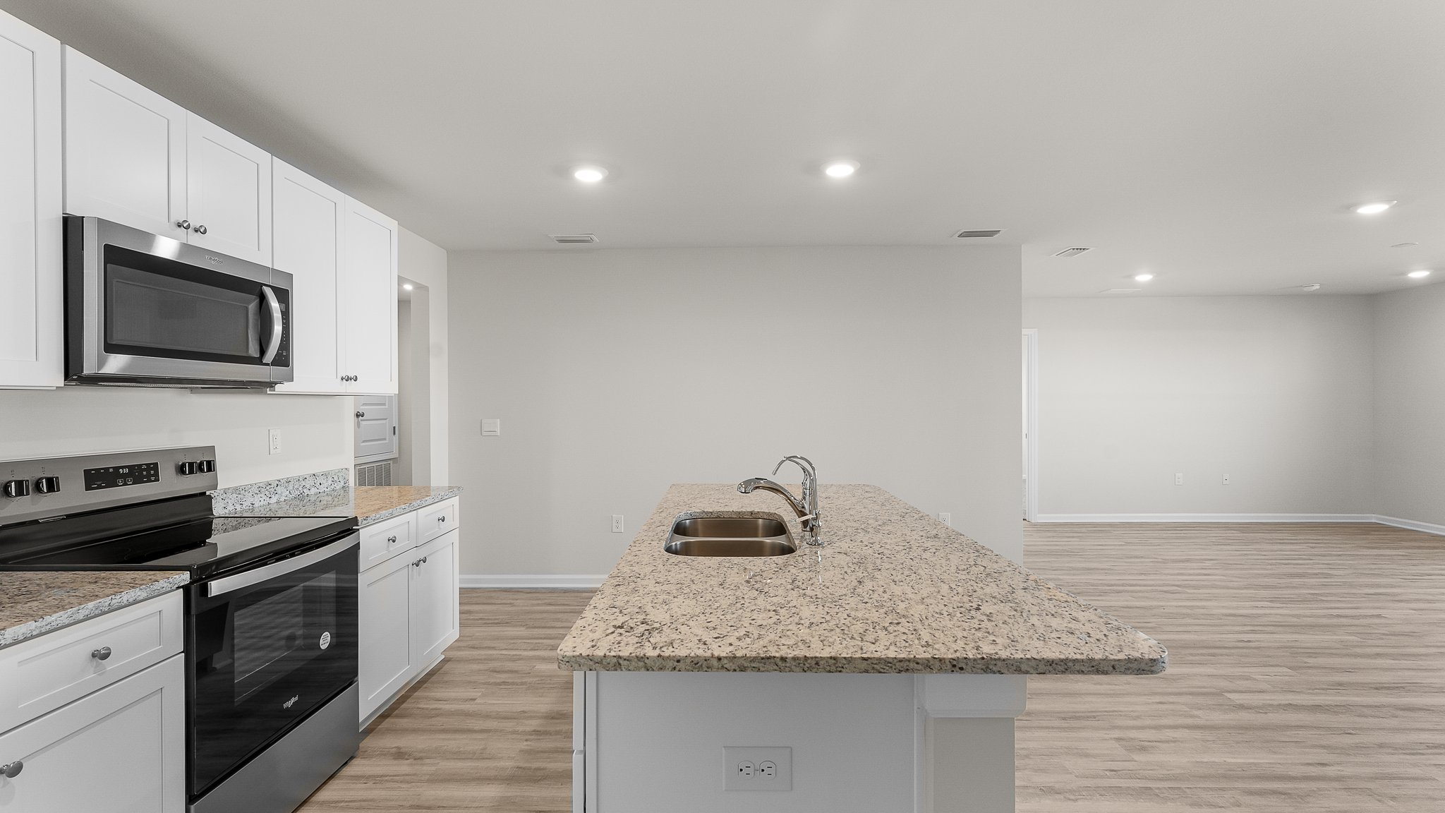 Kitchen island with white cabinets and stainless-steel appliances and granite countertops.
