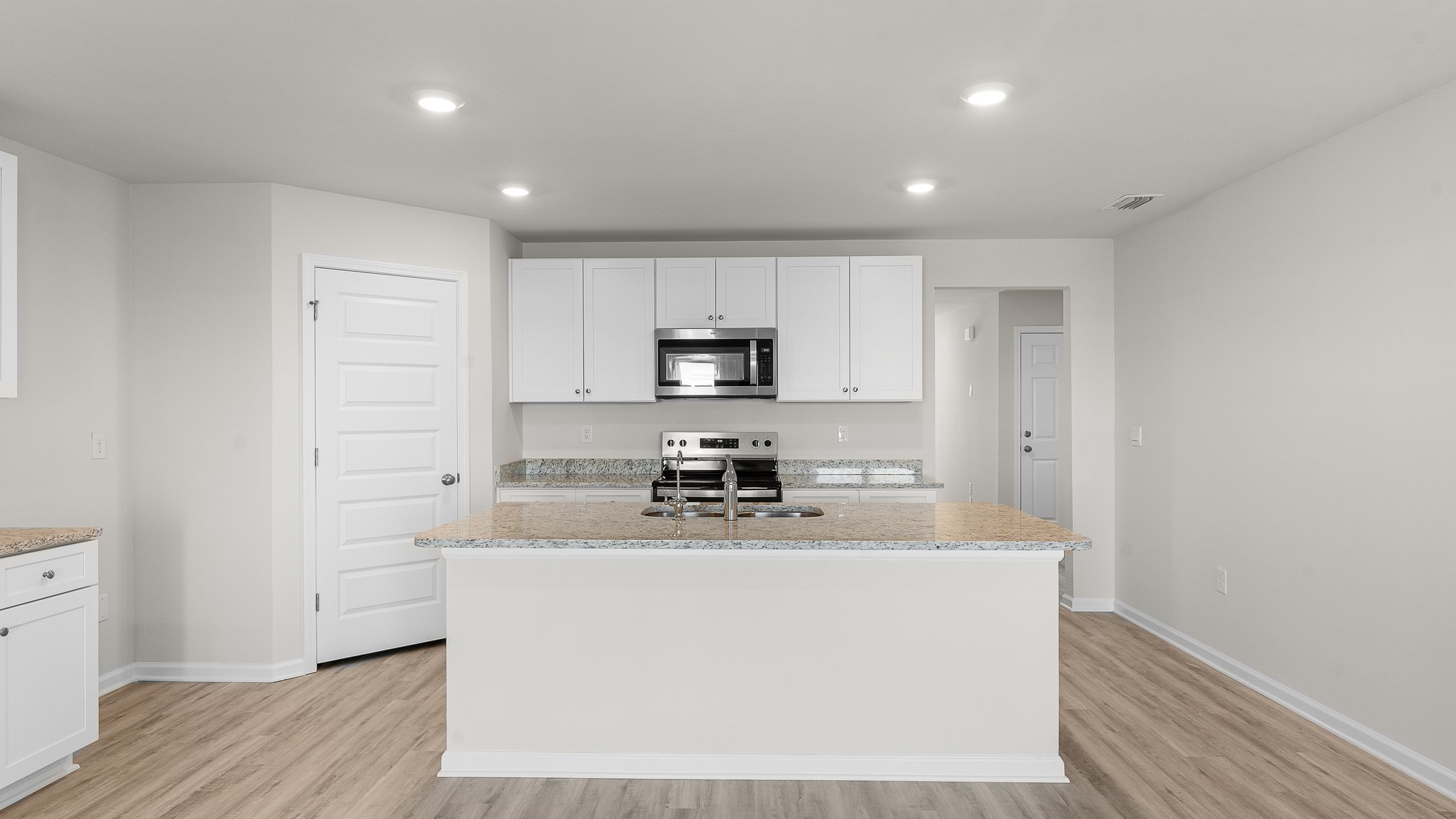 Kitchen island with white cabinets and stainless-steel appliances and granite countertops and pantry.