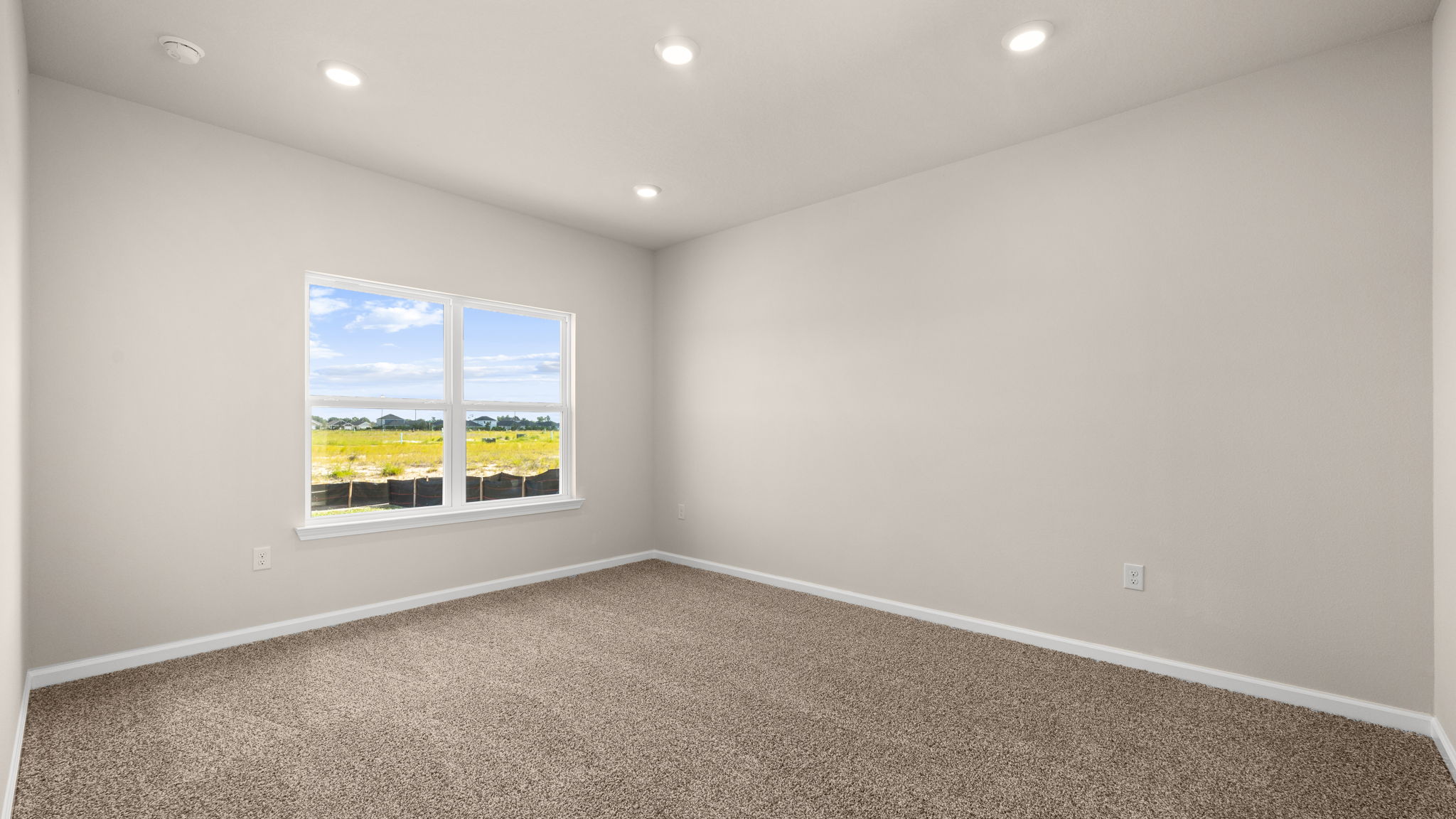 Primary bedroom with carpet flooring and windows.