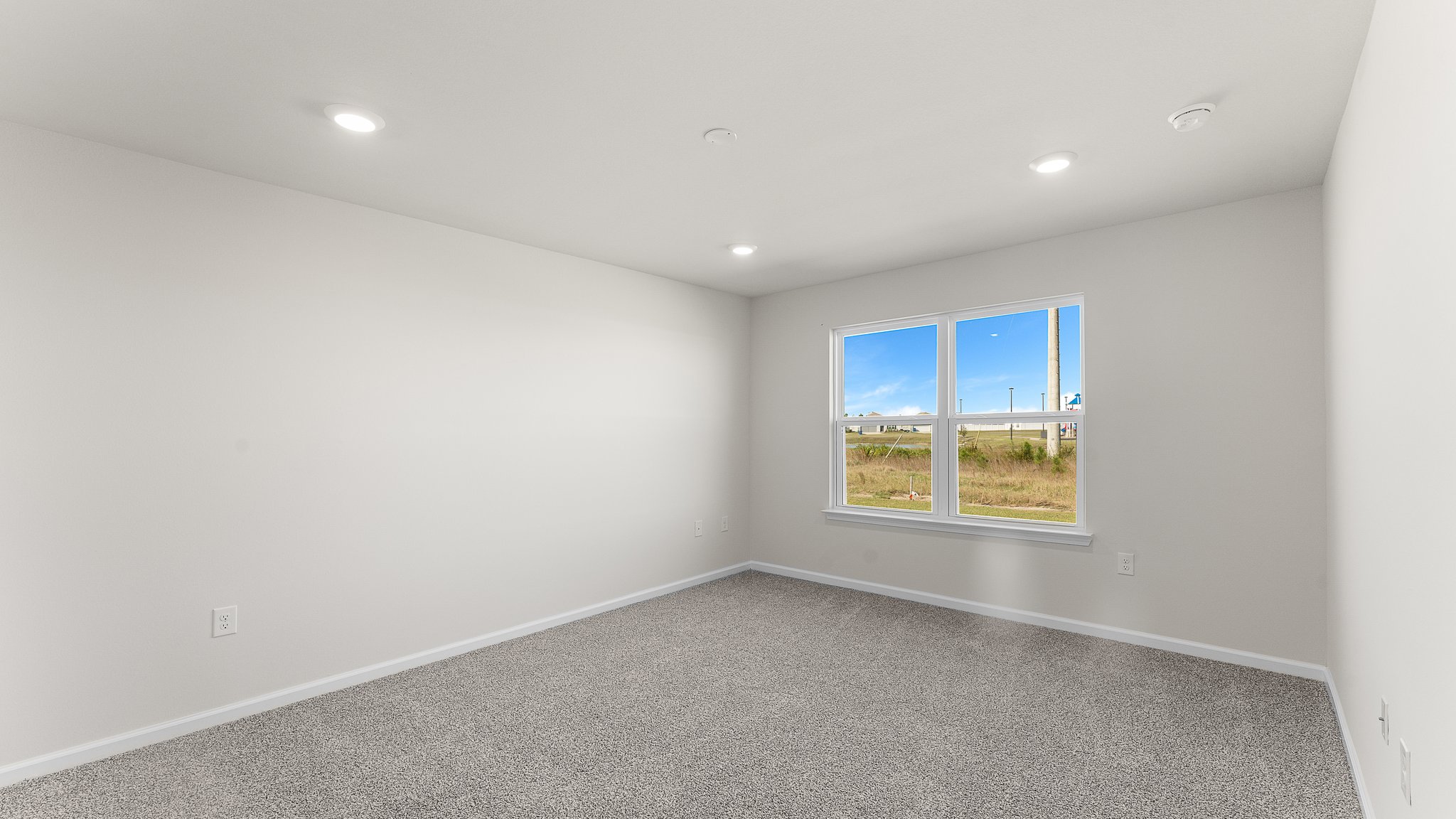 Primary bedroom with carpet floors and two windows.