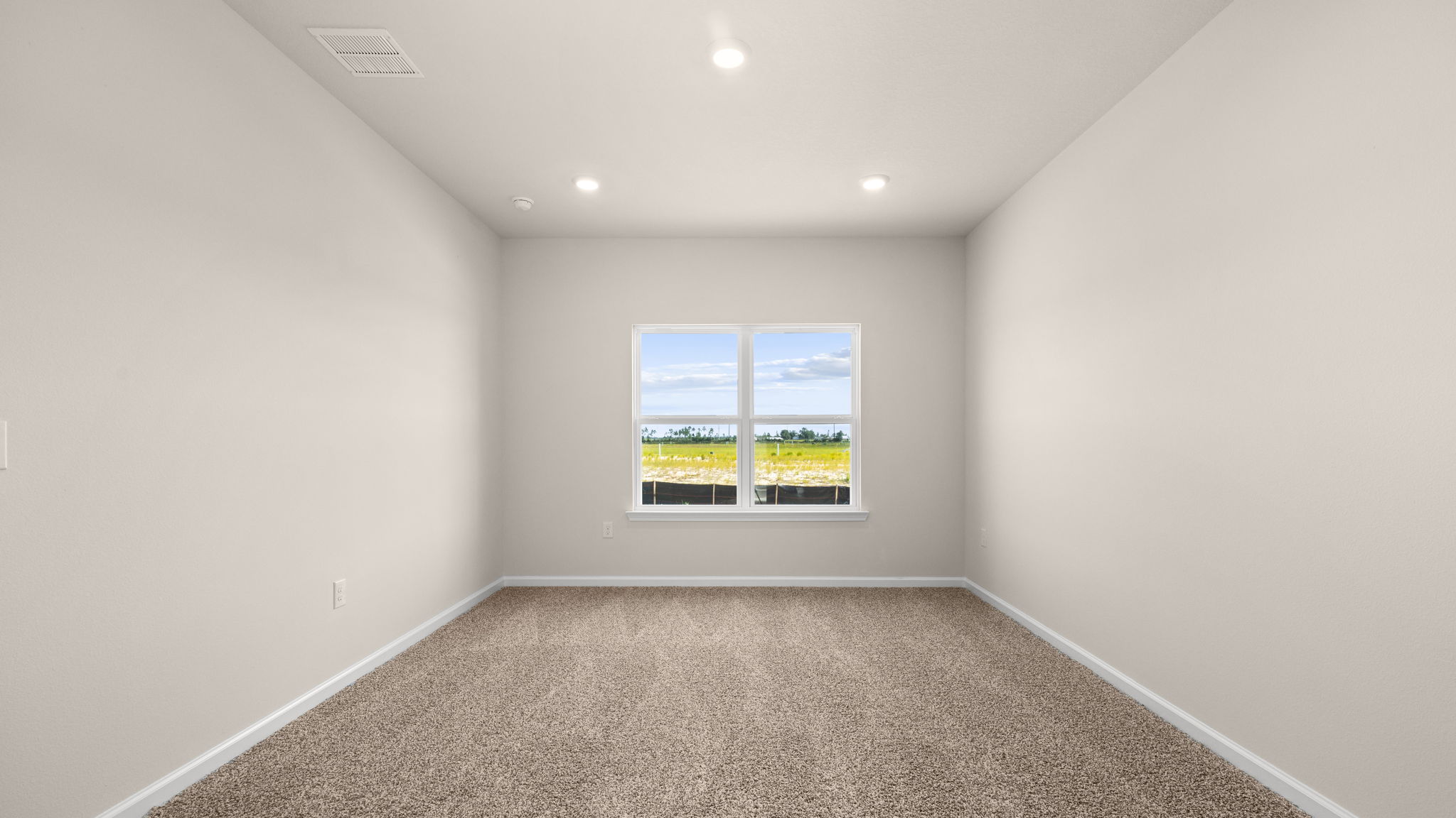 Primary bedroom with carpet flooring and windows.