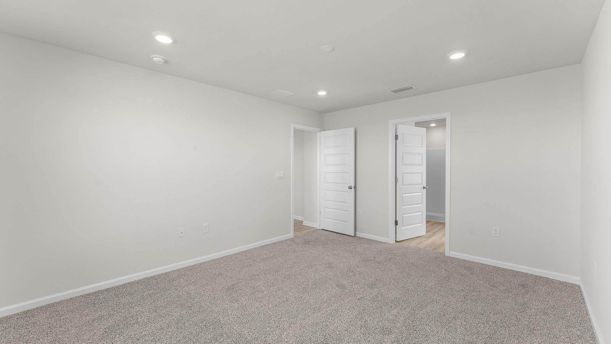 Primary bedroom with carpet floors and bathroom entrance.