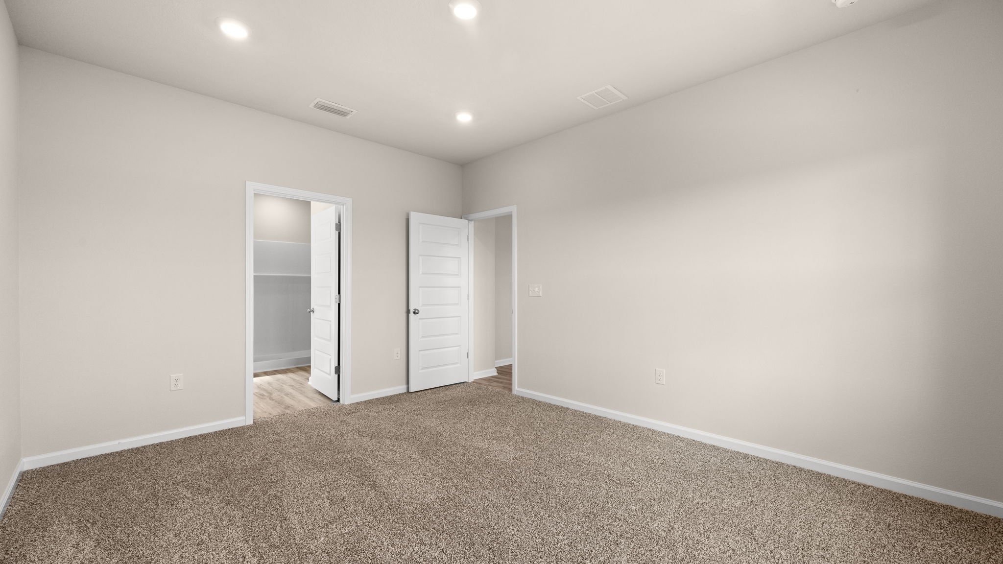 Primary bedroom with carpet floors and bathroom entrance.