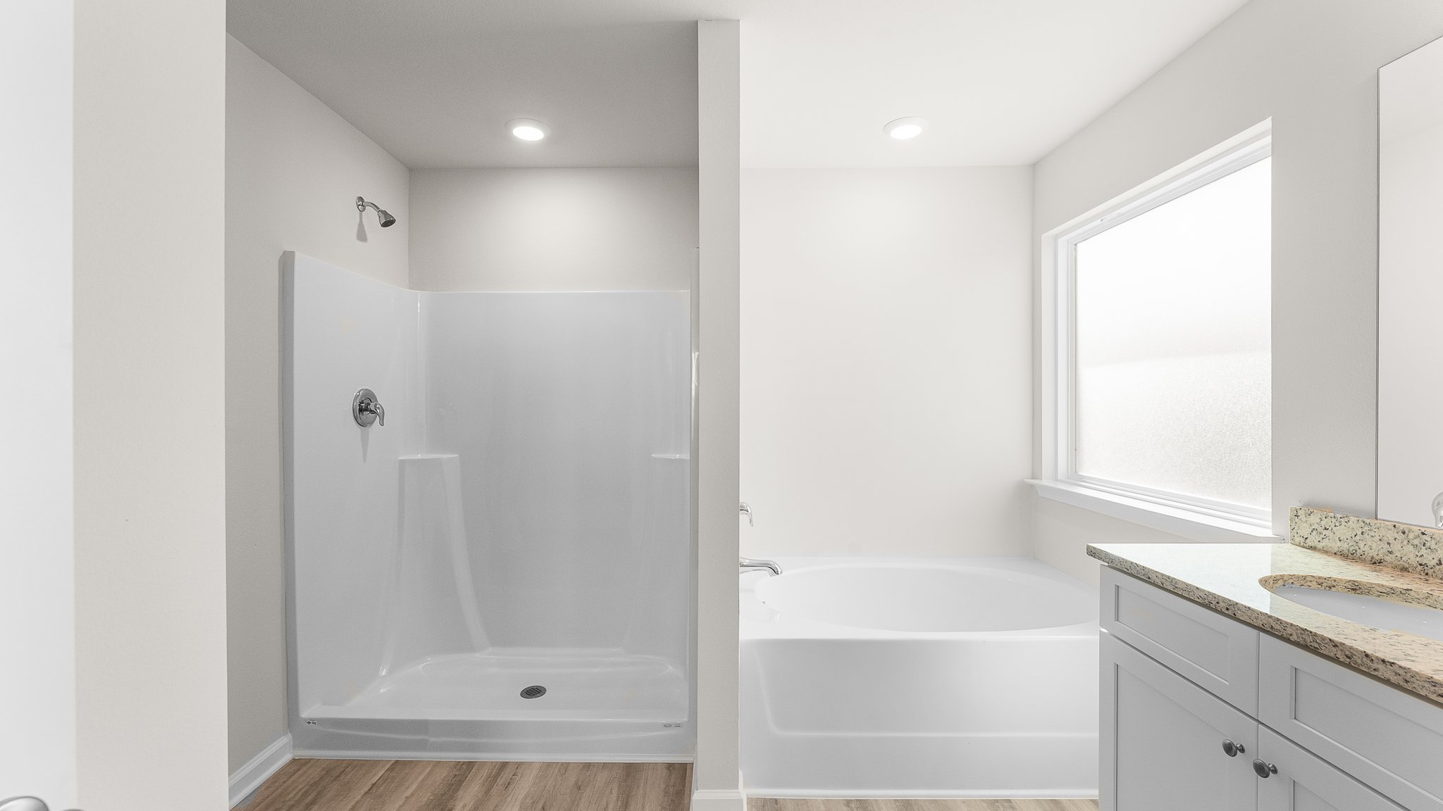 Primary bathroom with granite countertops and double vanity and white cabinets and tub and shower.