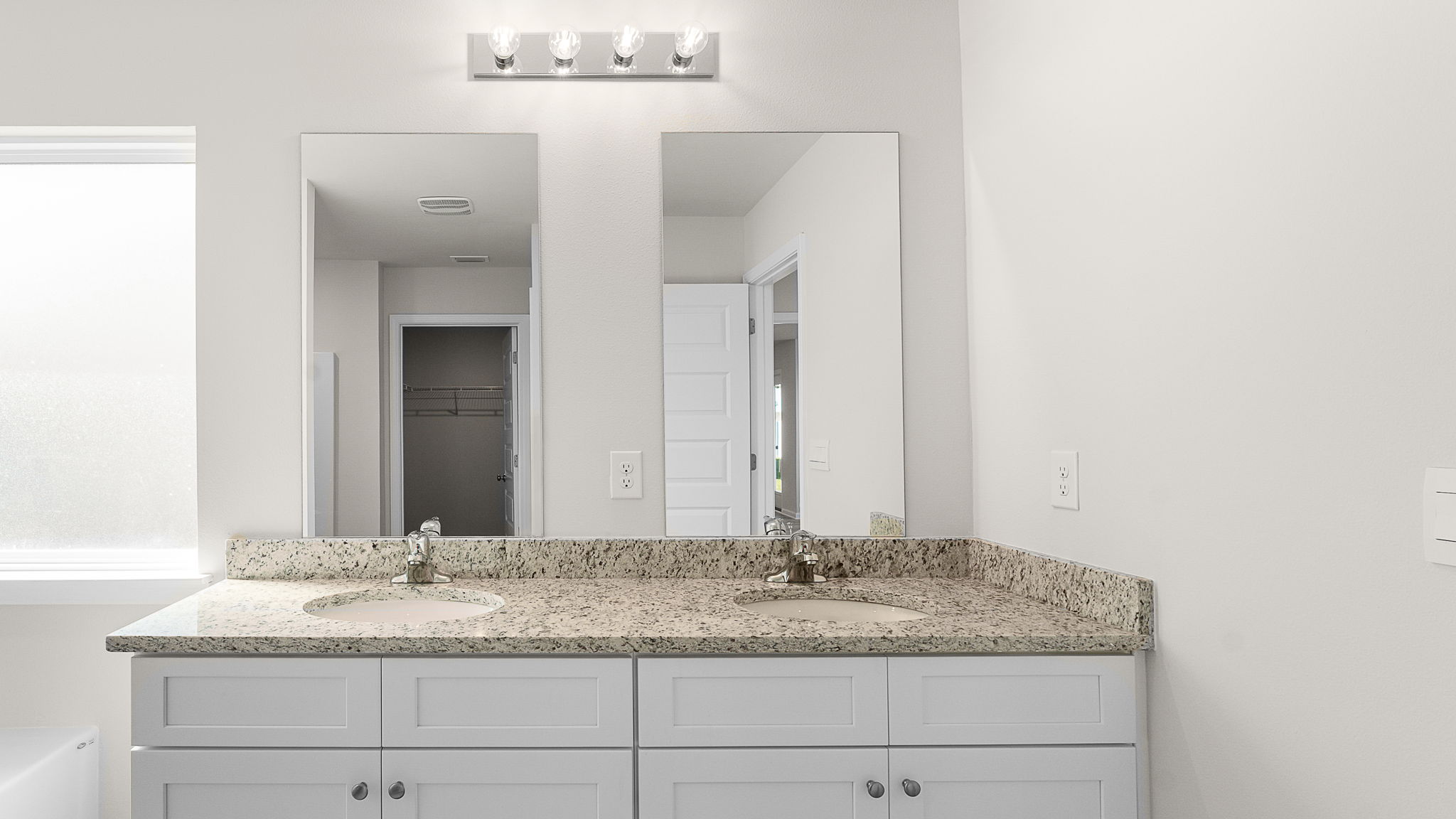 Primary bathroom with granite countertops and double vanity.