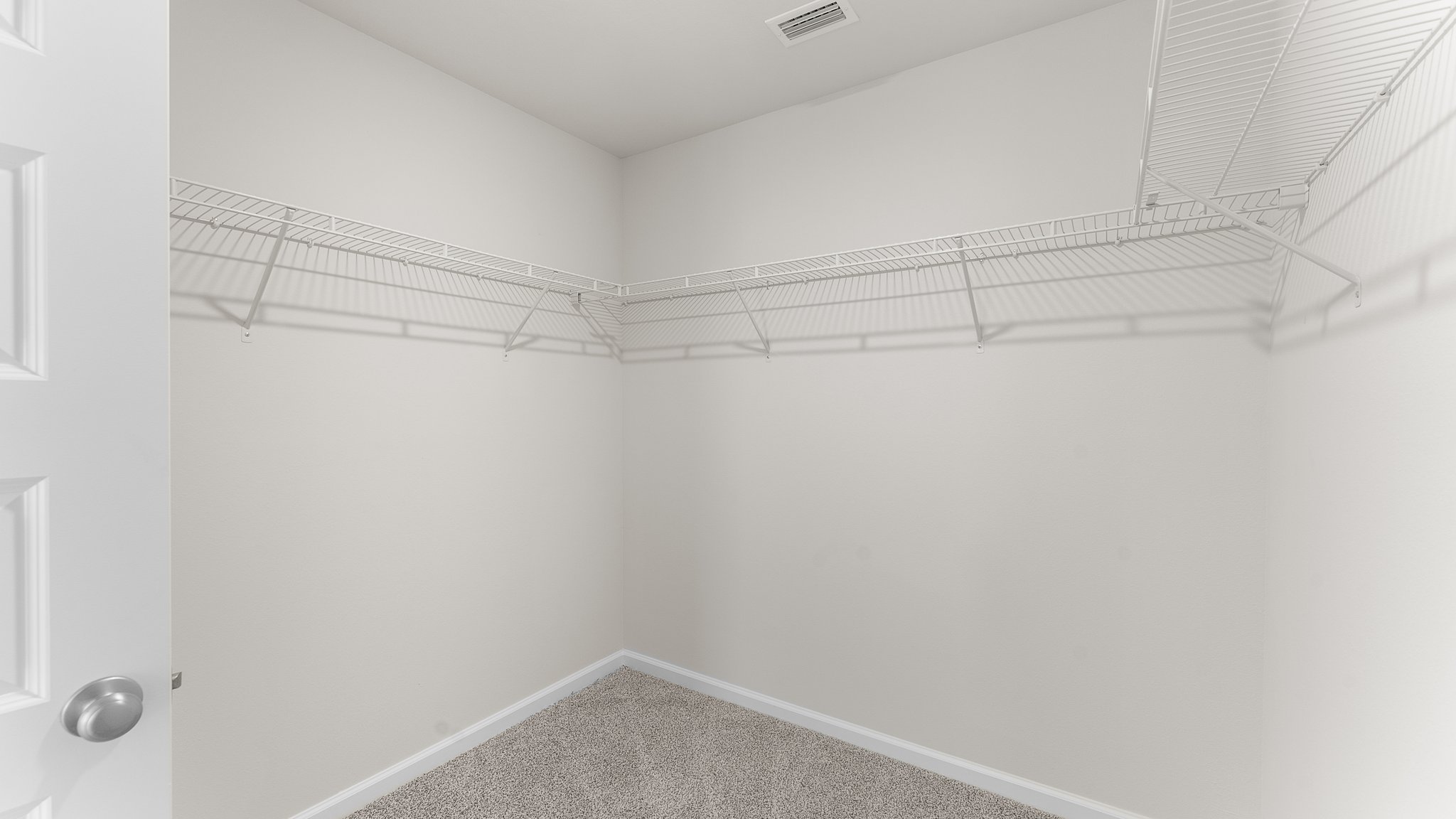 Primary bathroom walk in closet with ventilated shelving.