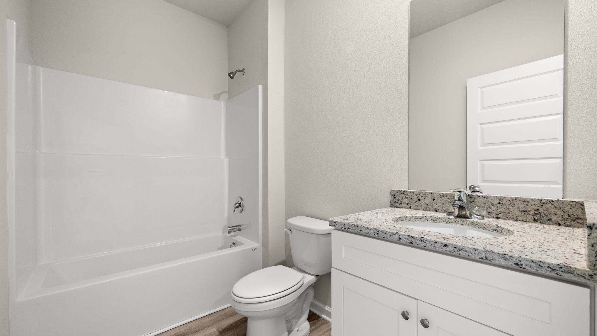 Bathroom with single vanity sink and granite countertops with white cabinets and EVP flooring and shower and toilet.
