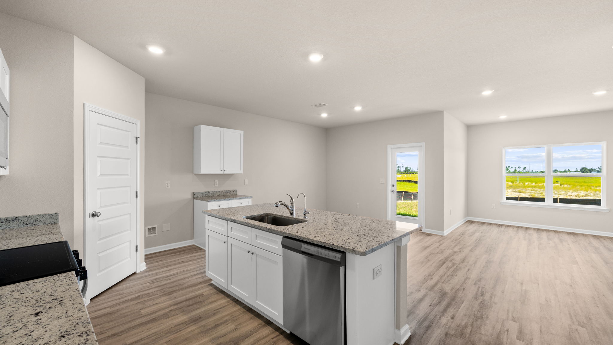 Kitchen with island and granite countertops with white cabinets and stainless-steel appliances.