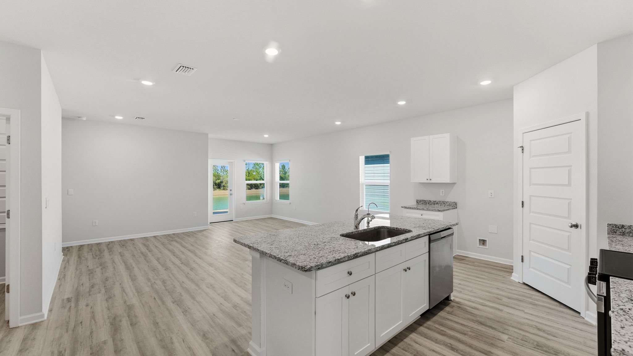 Kitchen view with island with white cabinets and granite countertops.