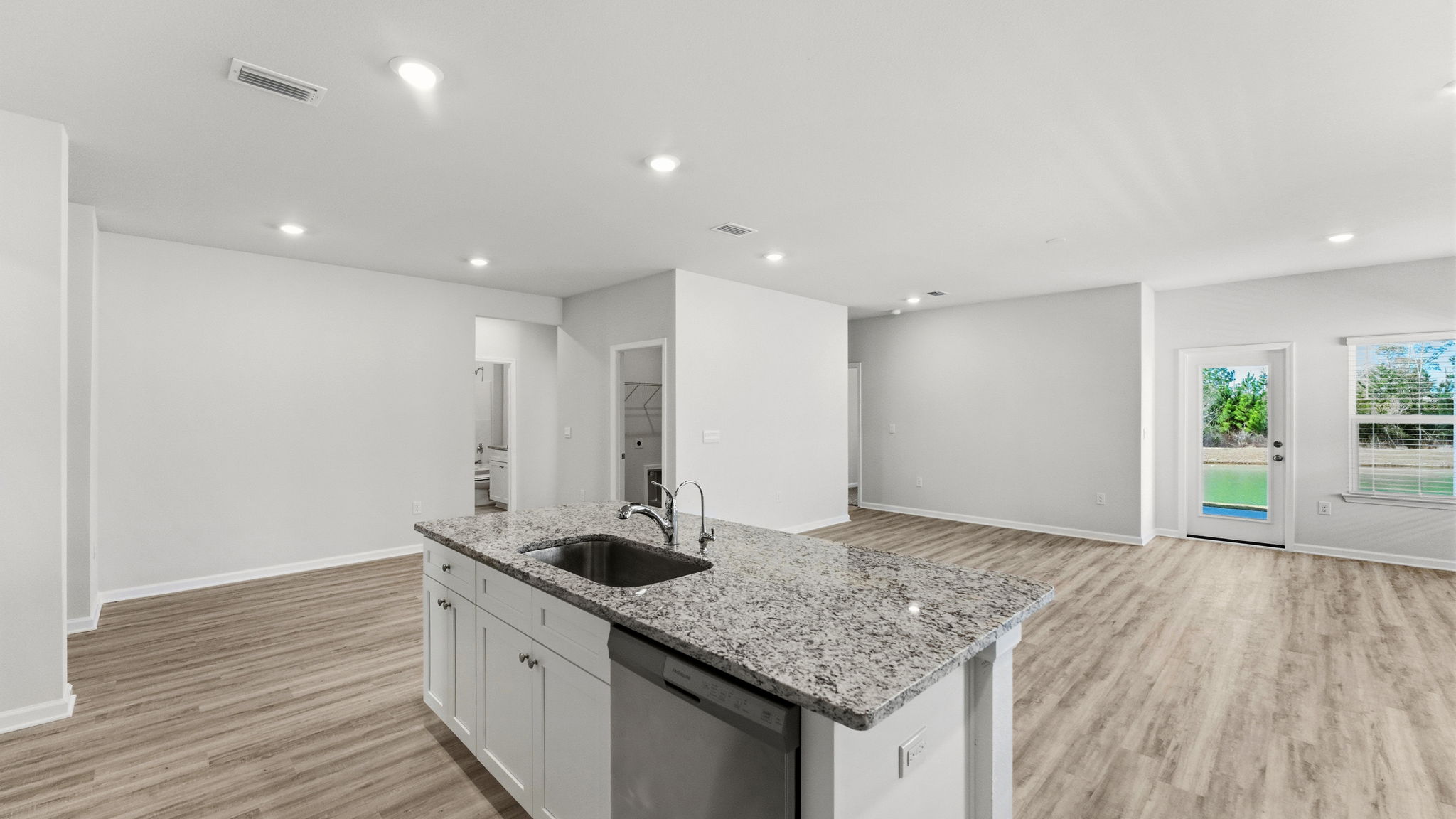 Kitchen view with island with white cabinets and granite countertops.