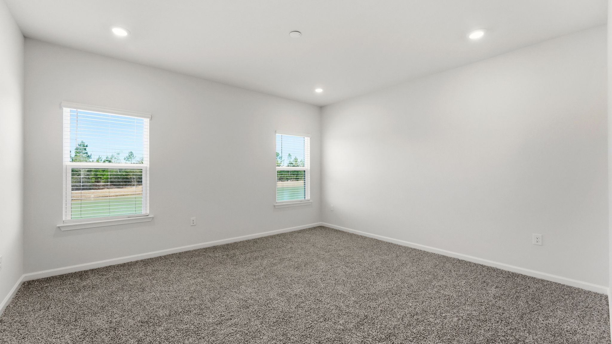 Primary bedroom with carpet flooring and windows.