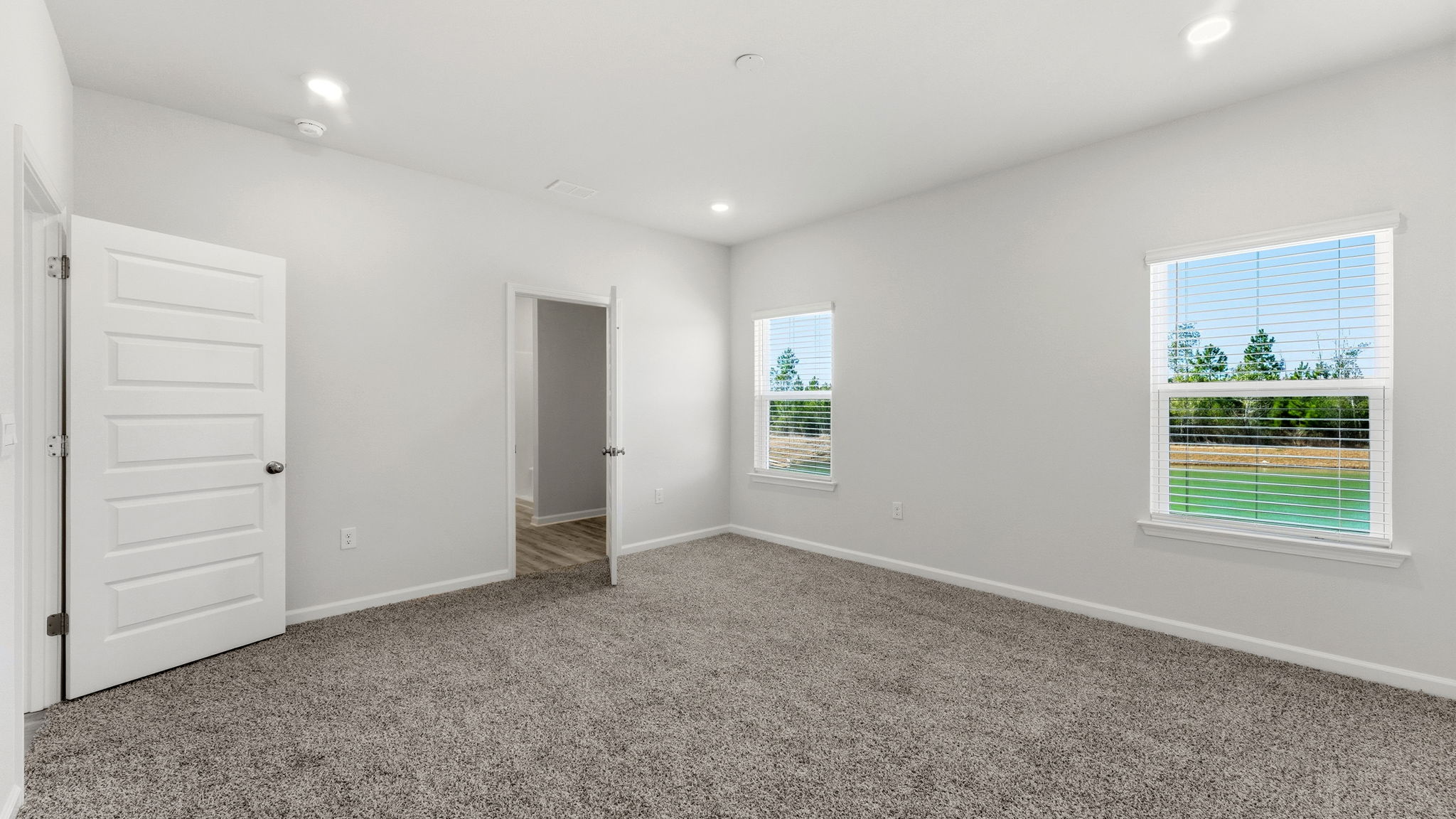 Primary bedroom with carpet floors and bathroom entrance.