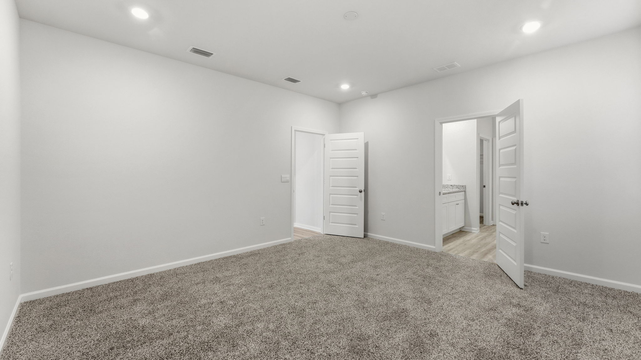Primary bedroom with carpet floors and bathroom entrance.