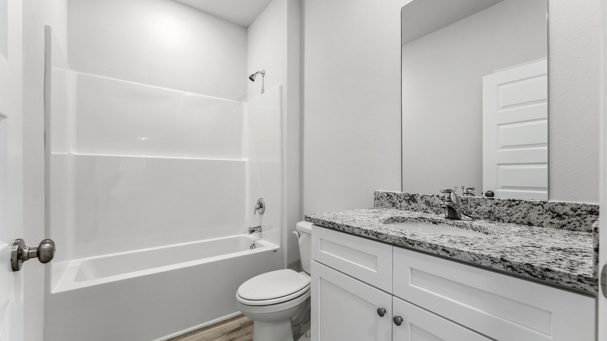 Bathroom with single vanity sink and granite countertops with white cabinets and EVP flooring and shower and toilet.