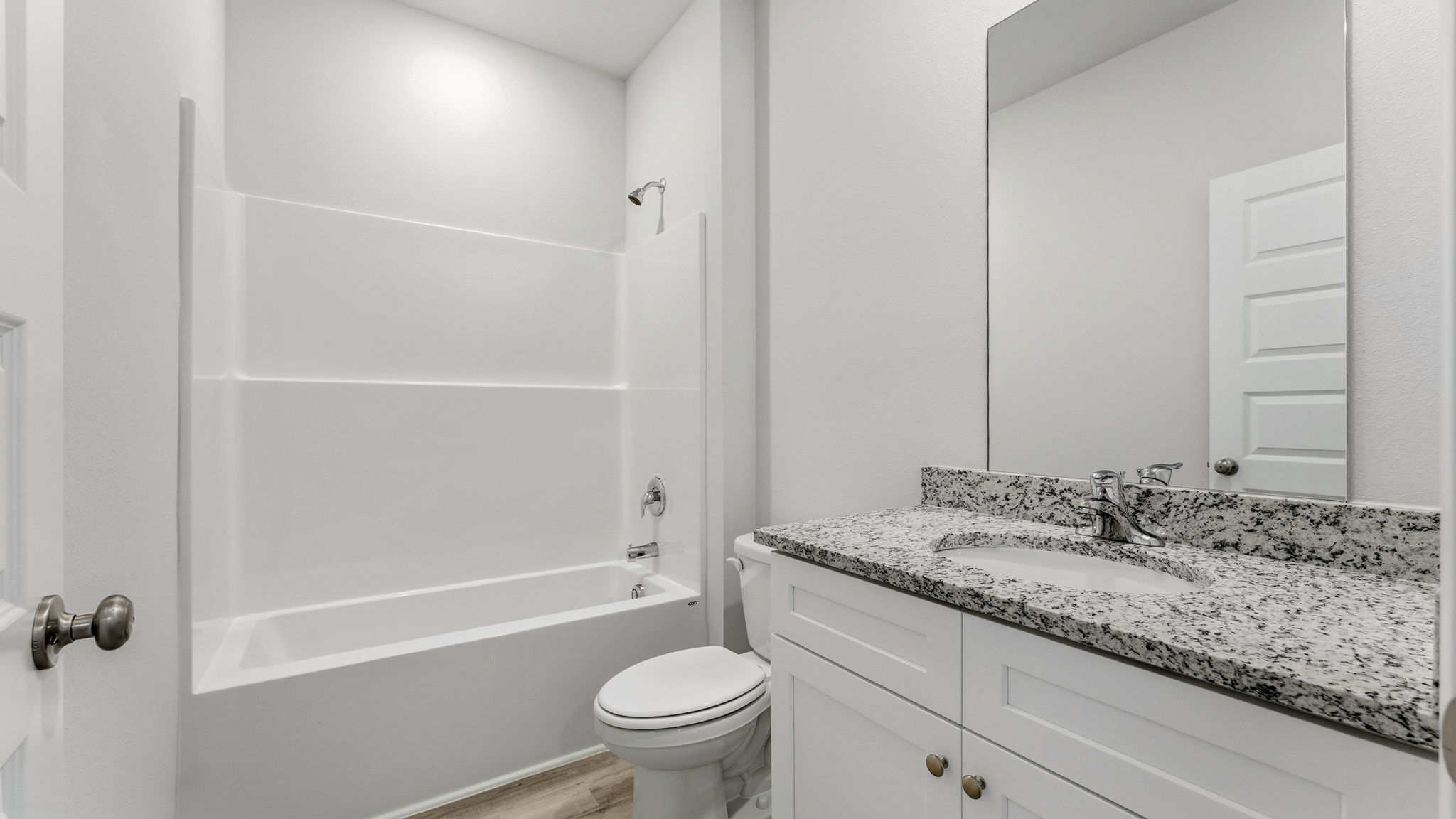 Bathroom with single vanity sink and granite countertops with white cabinets and EVP flooring and shower and toilet.