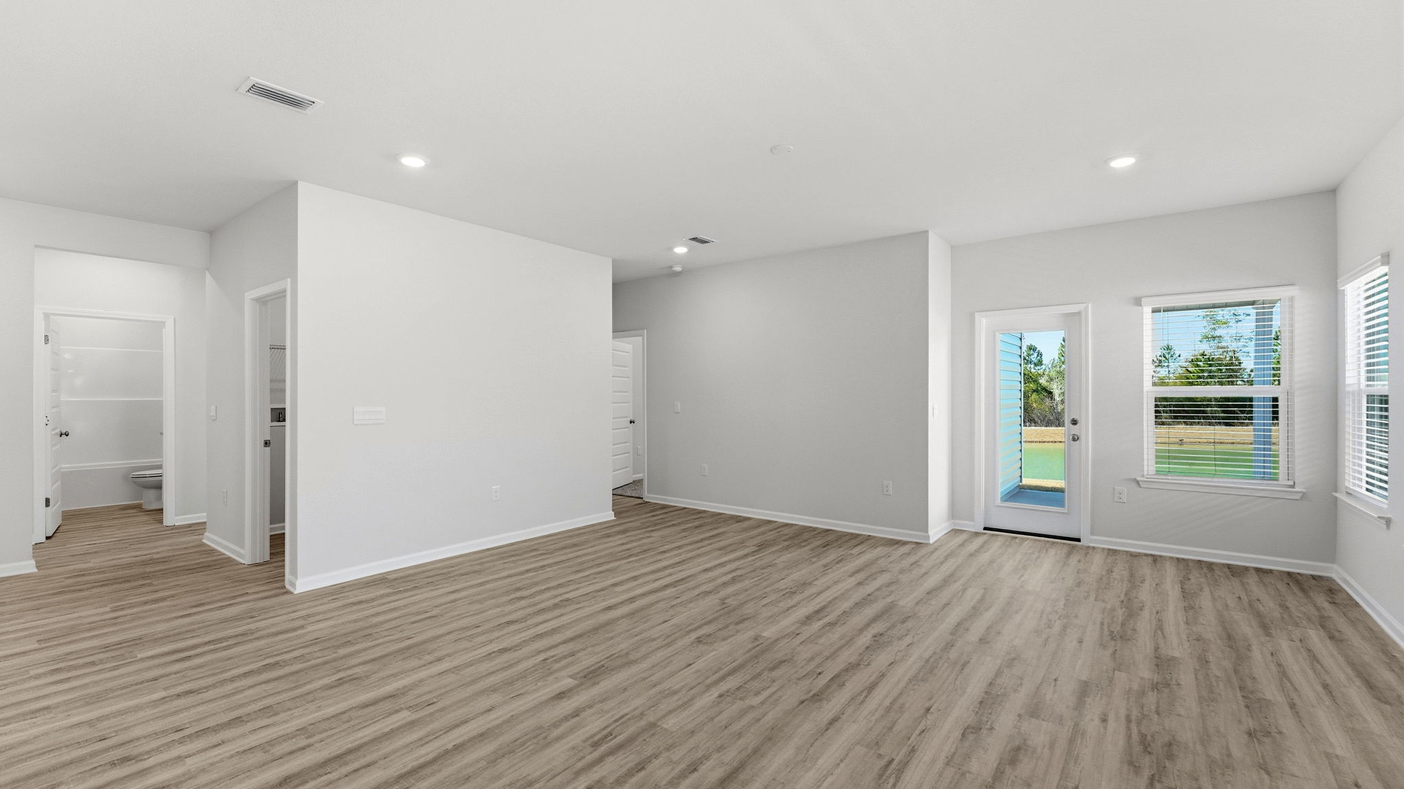 Living room with EVP flooring and back door next to bedrooms and laundry room.