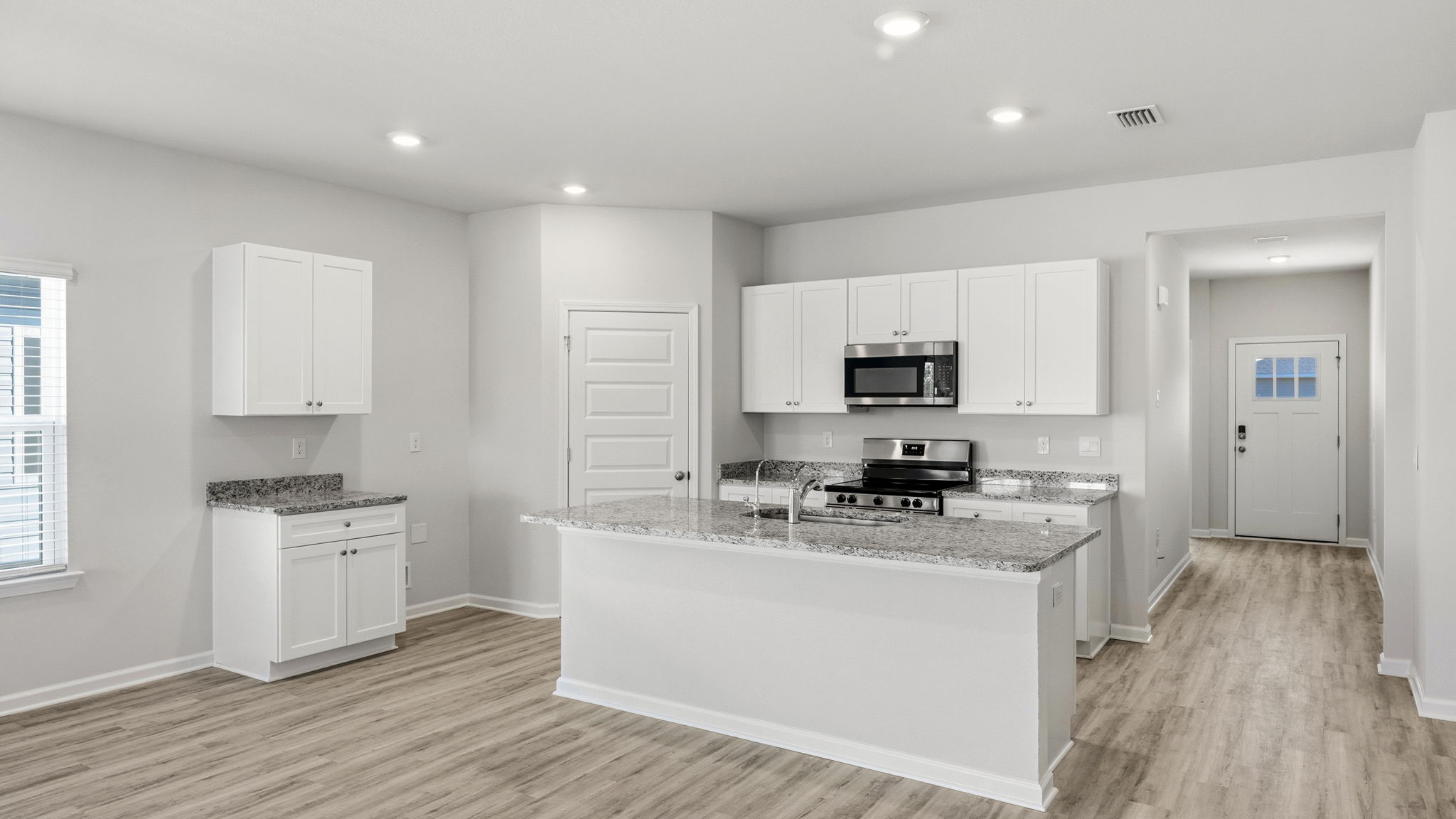 Kitchen with island and granite countertops with white cabinets and stainless-steel appliances.