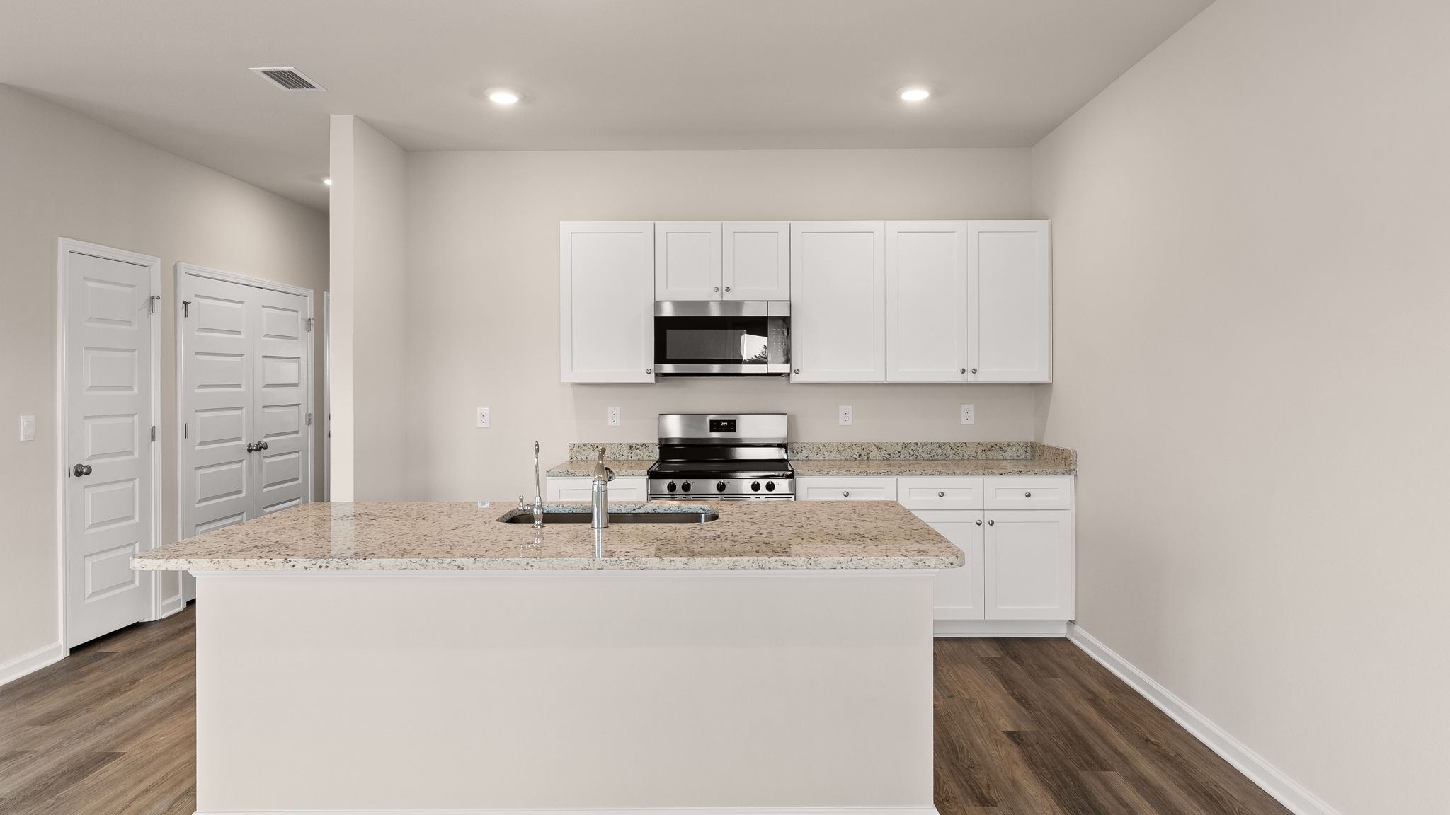 Kitchen with island and granite countertops with white cabinets and stainless-steel appliances.